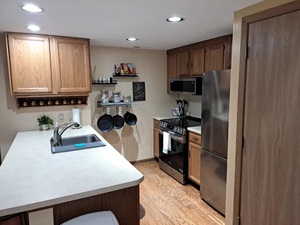 a kitchen with stainless steel appliances granite countertop a refrigerator a sink dishwasher a stove and white countertops with wooden floor