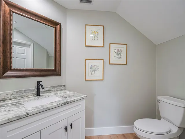 a bathroom with a granite countertop toilet sink and mirror