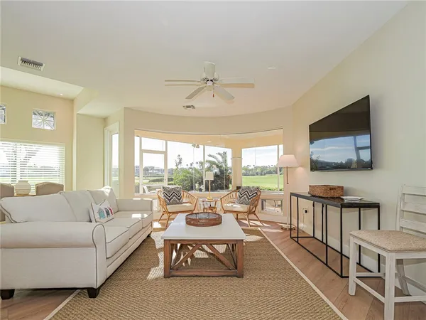 a living room with furniture a flat screen tv and a floor to ceiling window