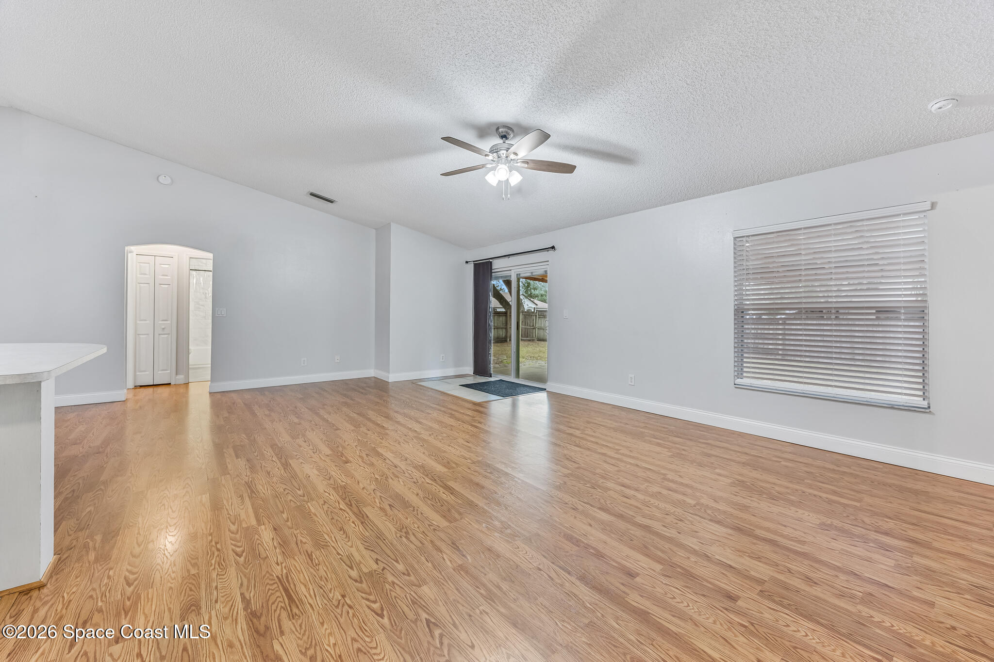 6185 Degan Road Cocoa, FL 32927 - Photo 14 of 30 a view of an empty room with wooden floor and a ceiling fan