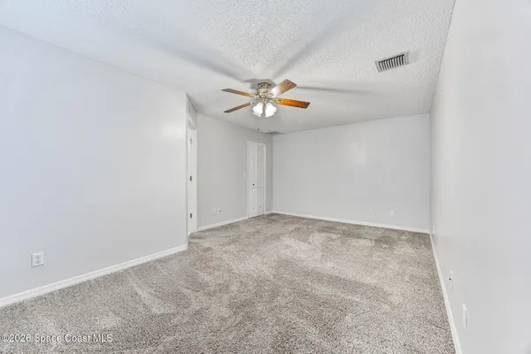 an empty room with chandelier fan and closet area