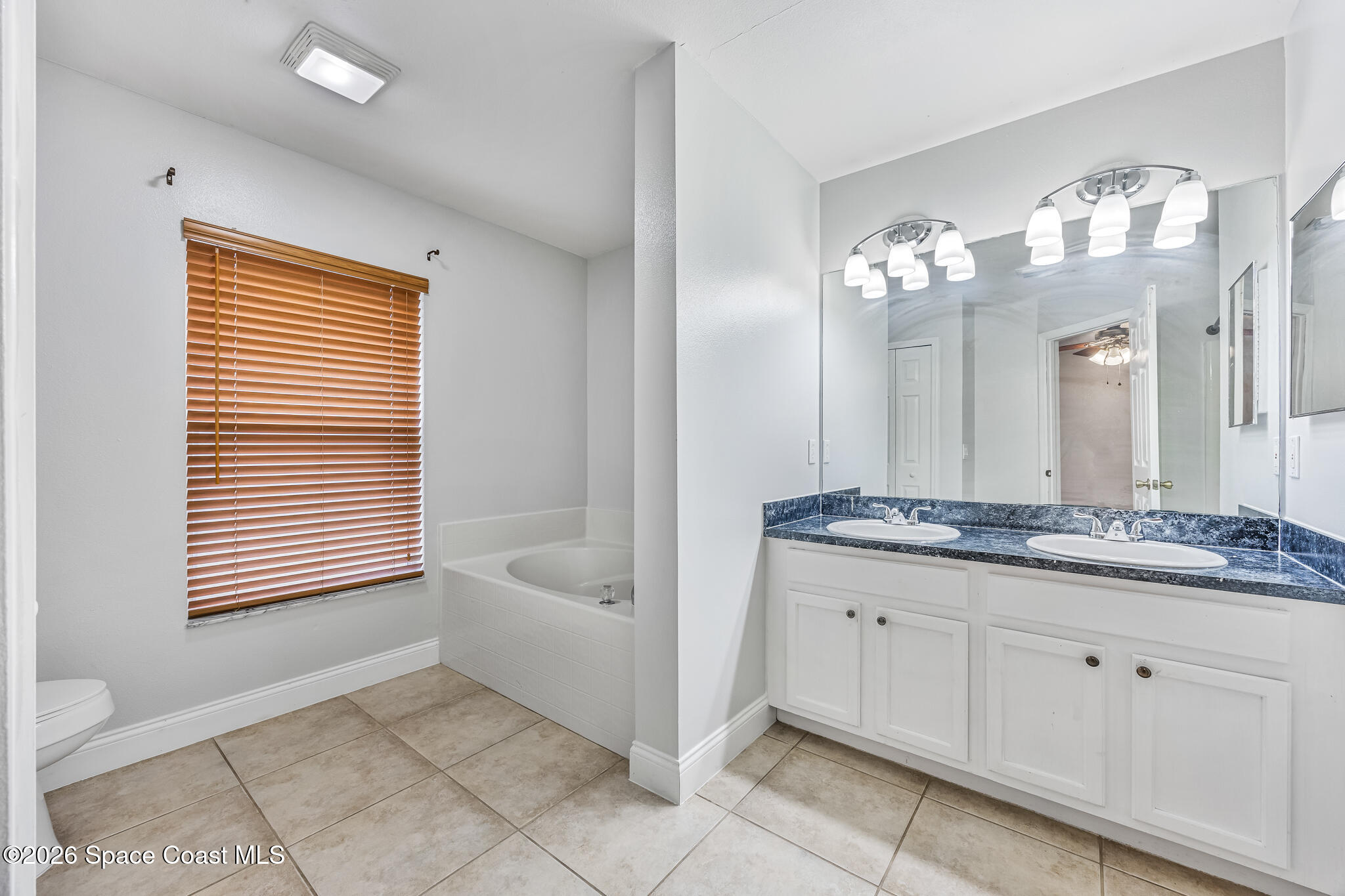 6185 Degan Road Cocoa, FL 32927 - Photo 18 of 30 a bathroom with a granite countertop sink a toilet a mirror and shower