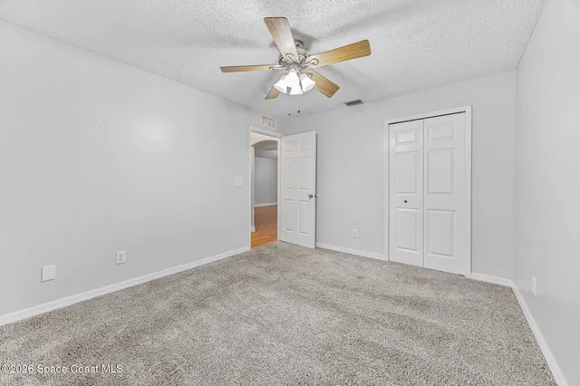 an empty room with windows and fan