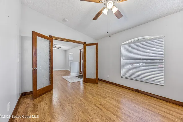 a view of an empty room with wooden floor and a window
