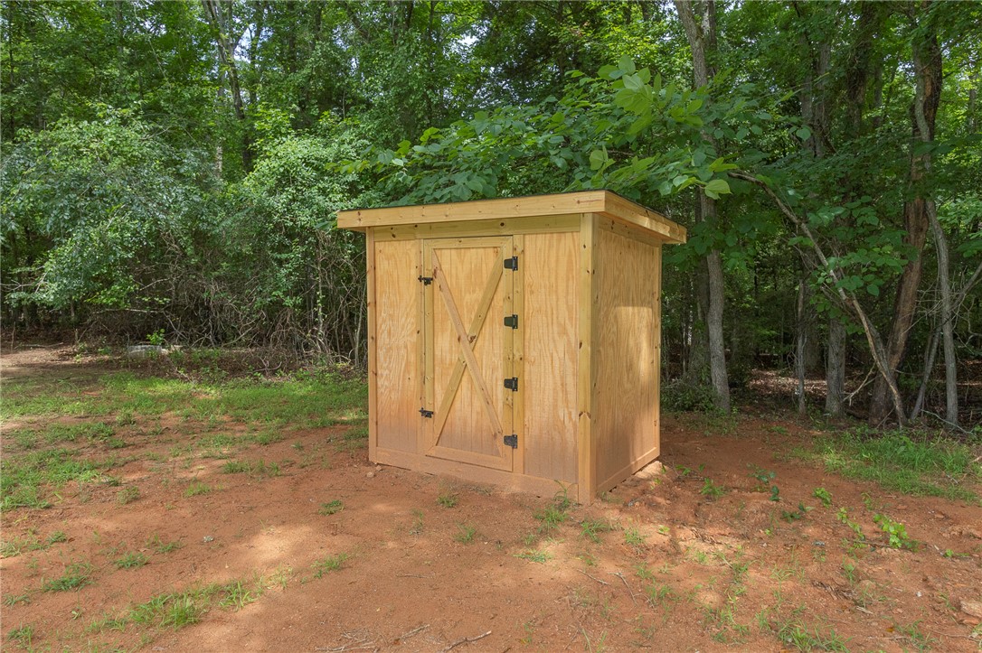 1317 East Broad Street Iva, SC 29655 - Photo 27 of 29 A new wooden shed provides practical storage amidst a natural, tree-lined setting.
