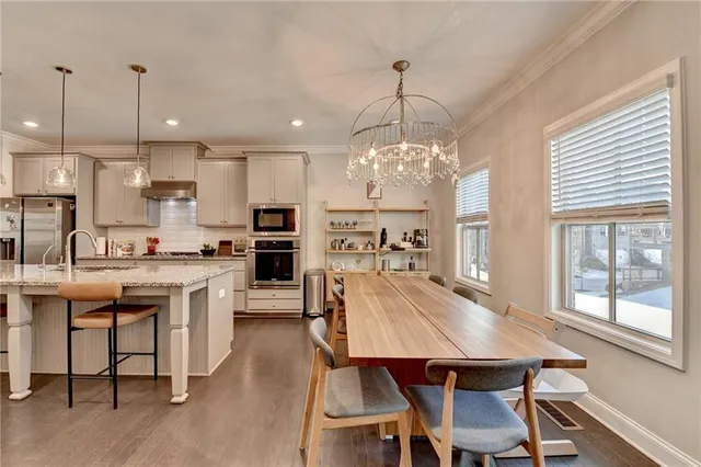 a view of a dining room and livingroom with furniture wooden floor a chandelier