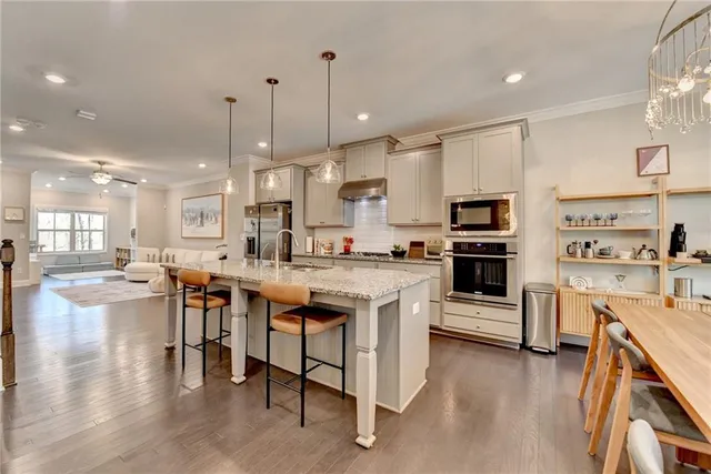 a large kitchen with cabinets chairs and wooden floor