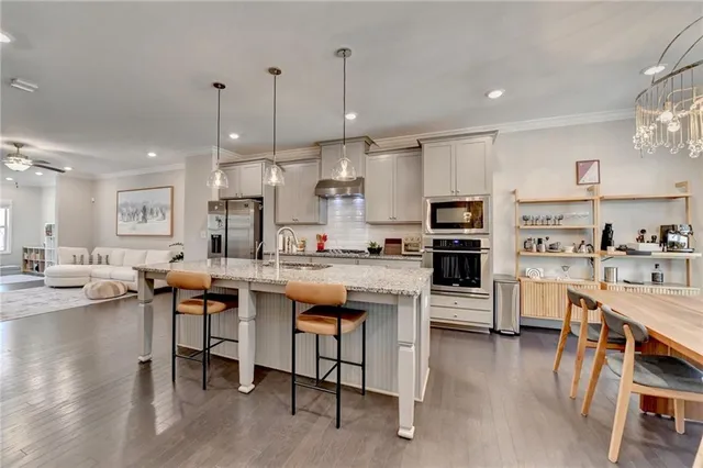 a large kitchen with cabinets chairs and wooden floor