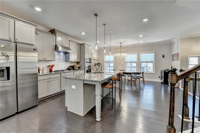 a kitchen with stainless steel appliances granite countertop a table chairs stove a refrigerator a sink a dining table and chairs