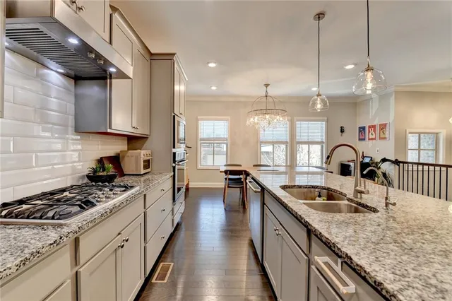 a large kitchen with stainless steel appliances granite countertop a sink a stove and a wooden floors