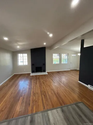 a view of empty room with window and wooden floor