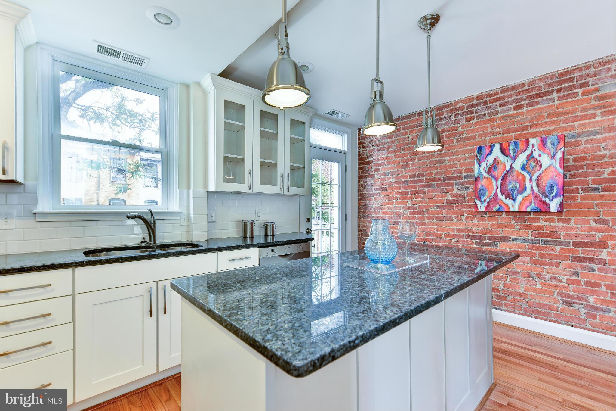 1749 Seaton Street Northwest Washington, DC 20009 - Photo 5 of 22 a kitchen with stainless steel appliances granite countertop a sink a counter space cabinets and wooden floor