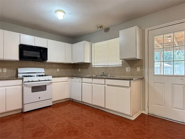 a kitchen with granite countertop white cabinets and white appliances