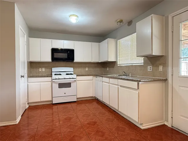 a kitchen with granite countertop white cabinets and white appliances
