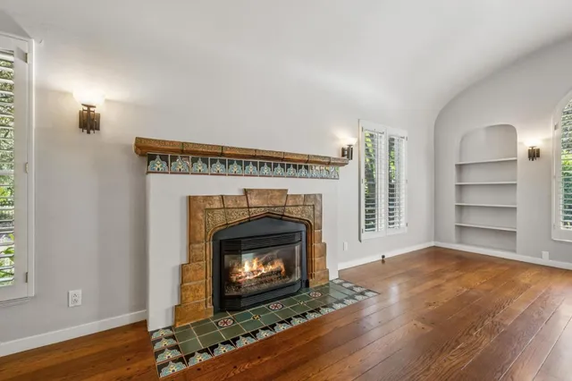 an empty room with wooden floor fireplace and windows