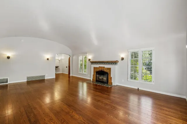 a view of an empty room with a window and wooden floor