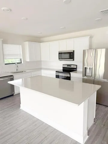 a kitchen with stainless steel appliances a stove a sink and a white wooden cabinets