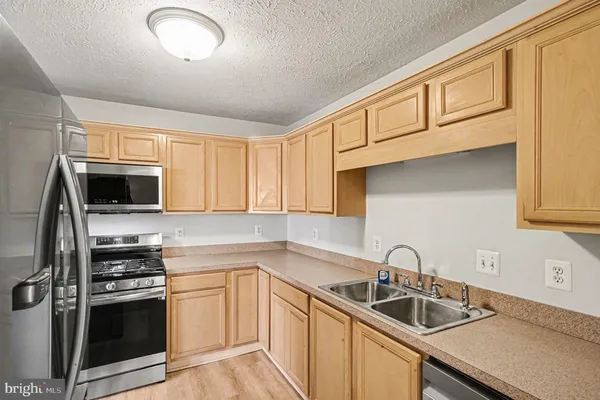 a kitchen with stainless steel appliances granite countertop a sink stove microwave and refrigerator