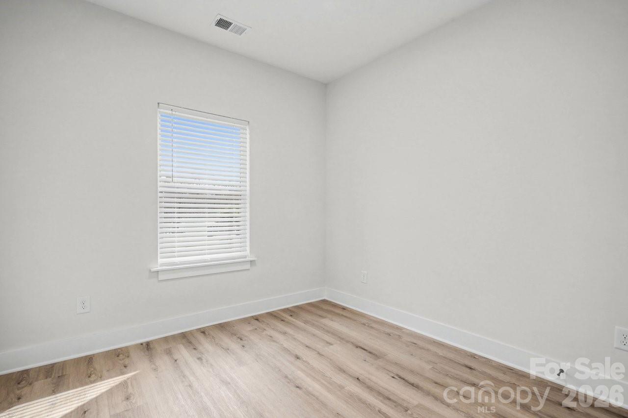 5626 Torrence Street Charlotte, NC 28269 - Photo 13 of 27 a view of an empty room with wooden floor and a window
