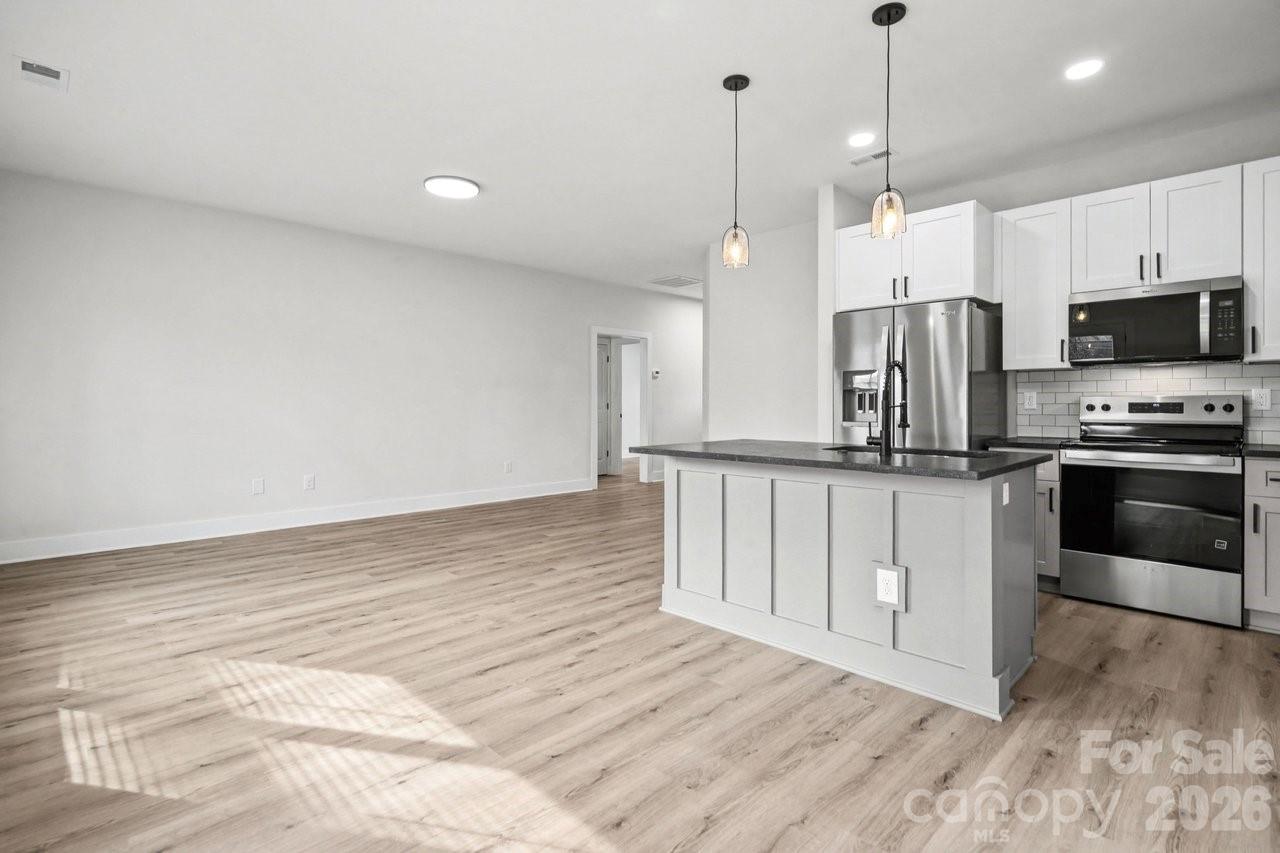 5626 Torrence Street Charlotte, NC 28269 - Photo 15 of 27 a kitchen with kitchen island a white counter top space stainless steel appliances and a center island