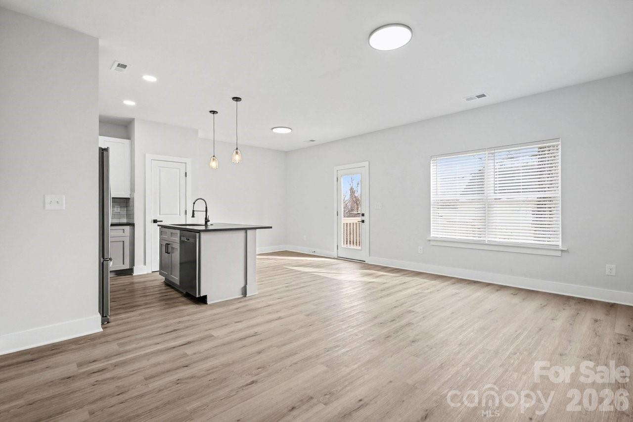5626 Torrence Street Charlotte, NC 28269 - Photo 17 of 27 an empty room with wooden floor kitchen view and a window