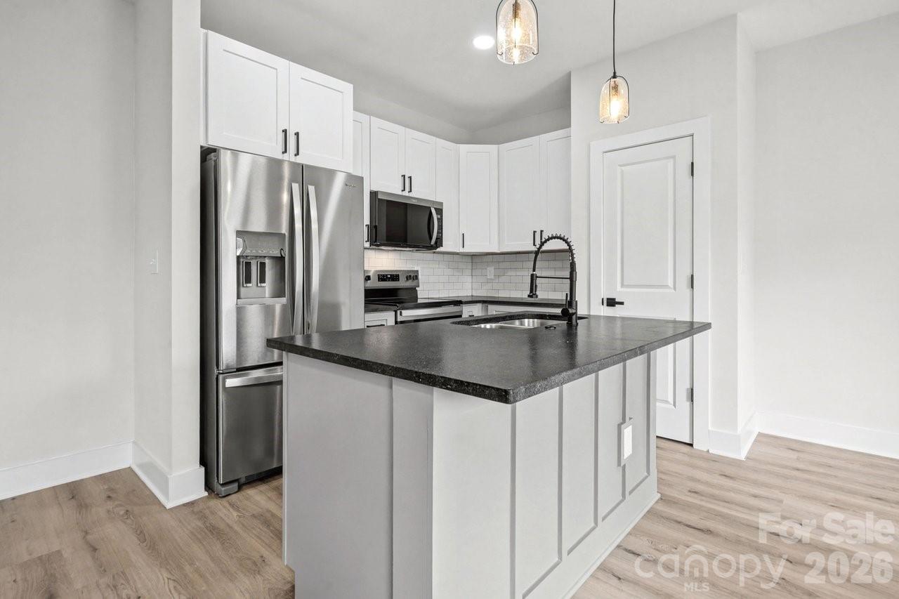 5626 Torrence Street Charlotte, NC 28269 - Photo 2 of 27 a kitchen with stainless steel appliances a sink stove refrigerator and cabinets