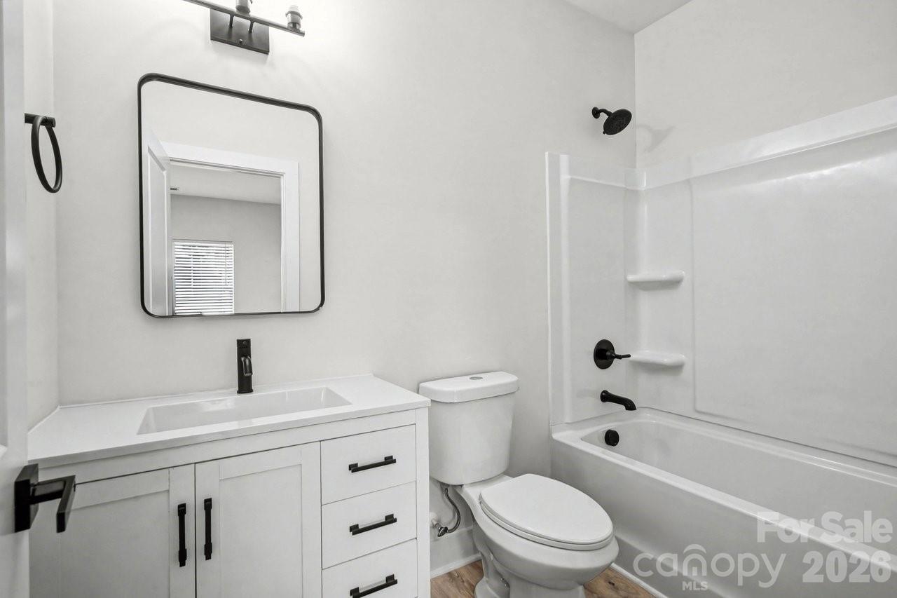 5626 Torrence Street Charlotte, NC 28269 - Photo 21 of 27 a bathroom with a toilet sink vanity tub and mirror
