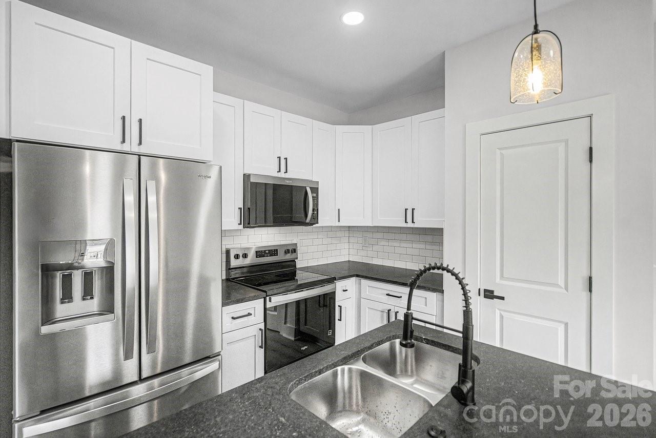 5626 Torrence Street Charlotte, NC 28269 - Photo 5 of 27 a kitchen with stainless steel appliances granite countertop a refrigerator a stove a sink and a refrigerator with wooden floor