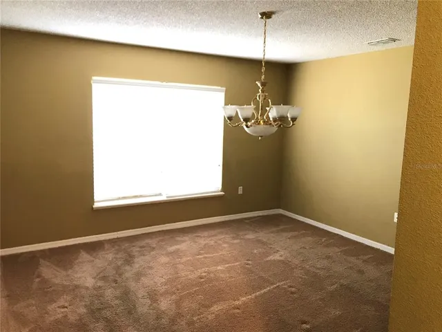 en empty room with windows and chandelier