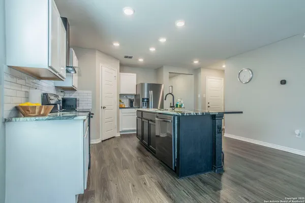 a living room with furniture and kitchen view with wooden floor