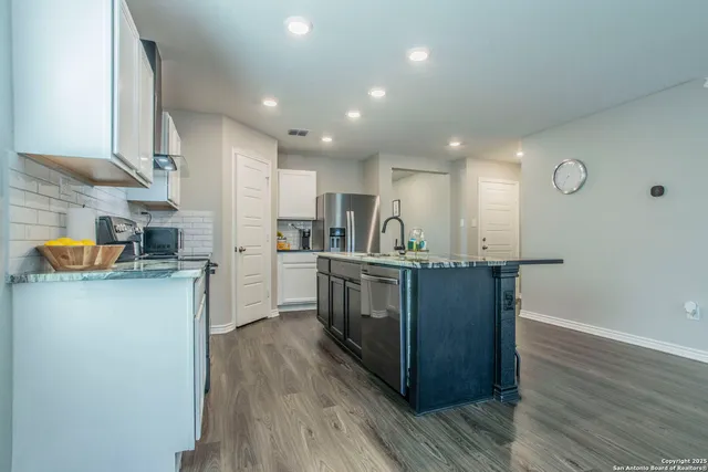 a living room with furniture and kitchen view with wooden floor