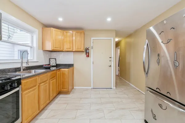 a large kitchen with stainless steel appliances granite countertop a refrigerator and a sink