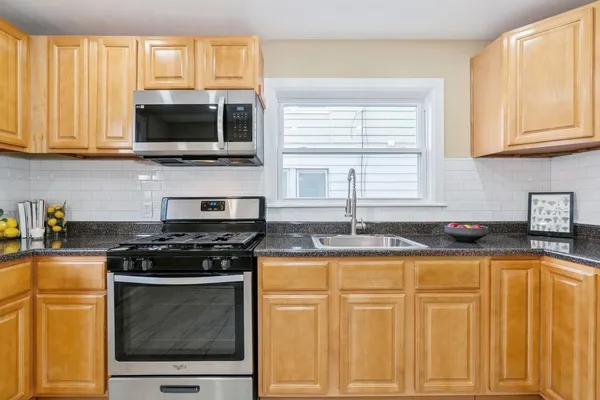 a kitchen with granite countertop a stove a sink and a microwave