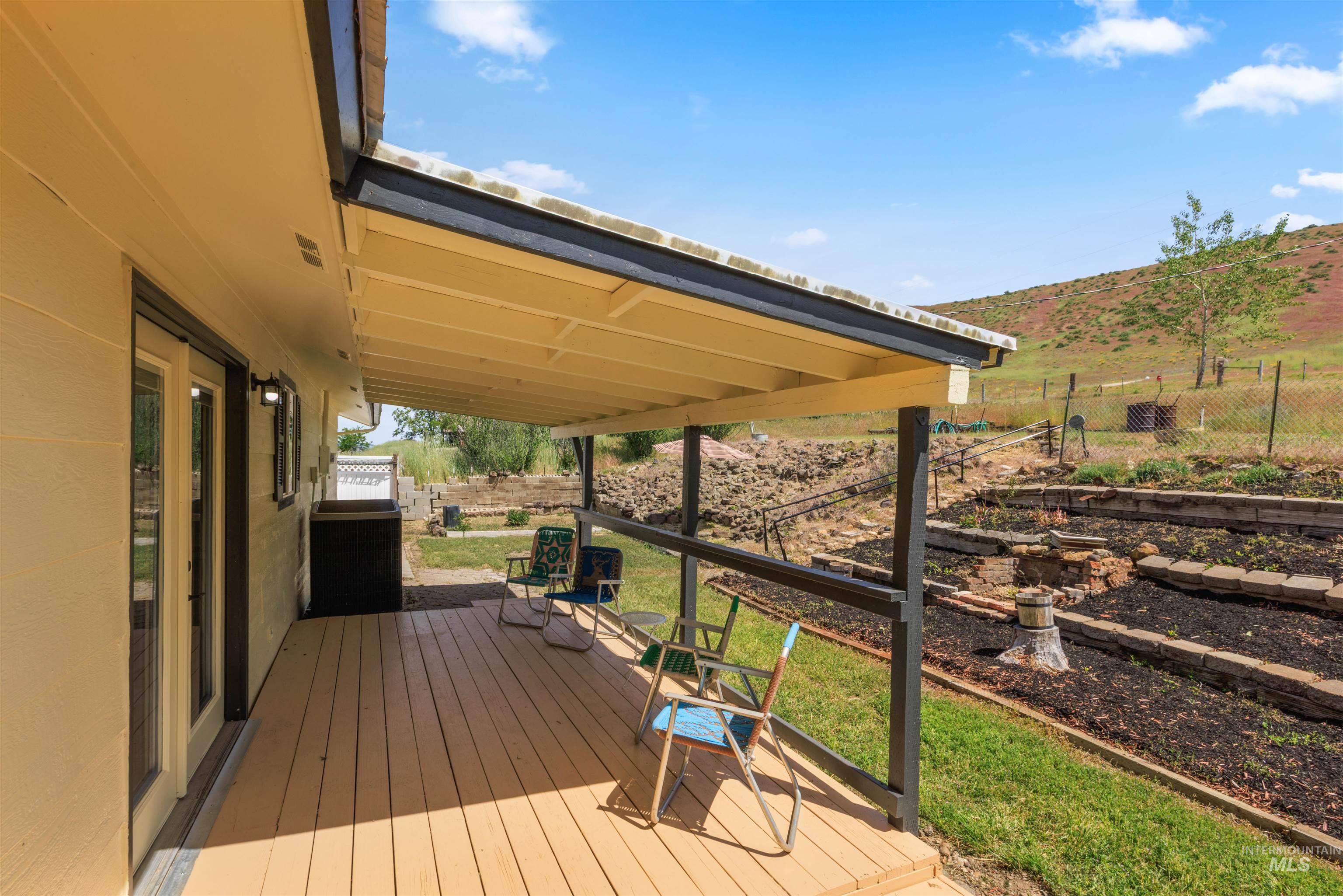 12184 Hill Road Payette, ID 83661 - Photo 31 of 35 Expansive covered deck featuring wood-finish flooring, direct outdoor access via glass doors, and a natural landscape backdrop