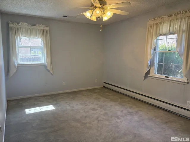 en empty room with windows and chandelier fan