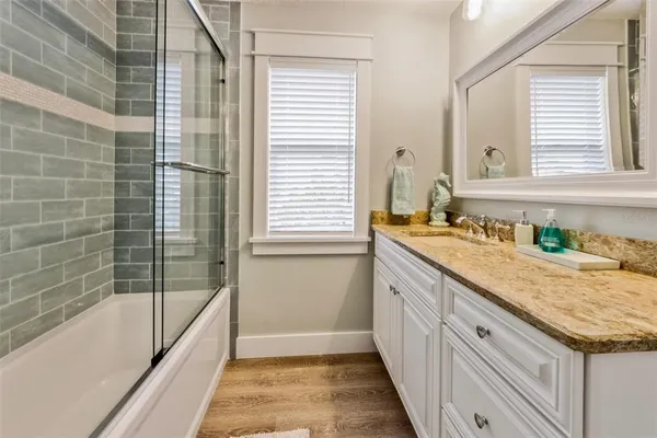 a bathroom with a granite countertop sink and a bathtub