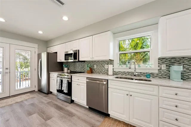 a kitchen with granite countertop white cabinets and stainless steel appliances