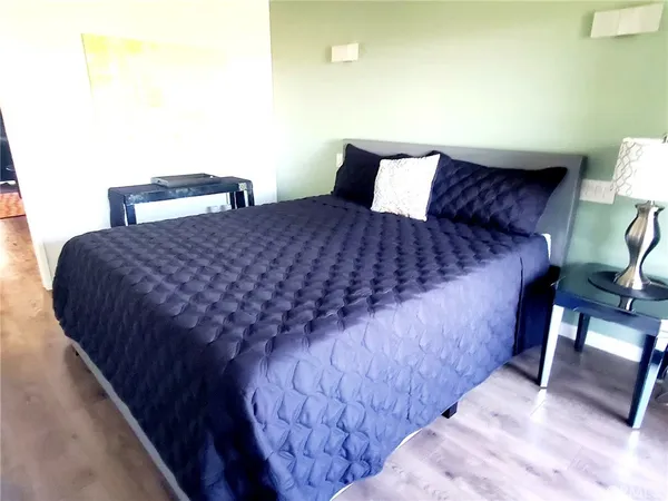 a bed sitting in a bedroom next to a lamp with a chair and a potted plant