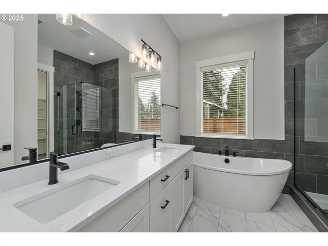 a bathroom with a white tub a sink a window and a shower