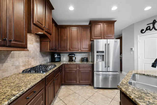 a kitchen with stainless steel appliances granite countertop a refrigerator stove and sink