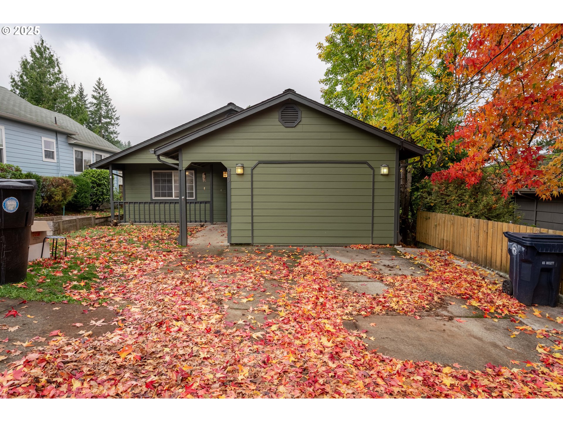 a backyard of a house with wooden fence and large tree