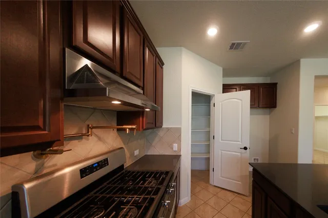 a kitchen with stainless steel appliances granite countertop a refrigerator and a stove top oven
