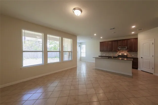 a large kitchen with stainless steel appliances granite countertop a large counter top a stove and a sink