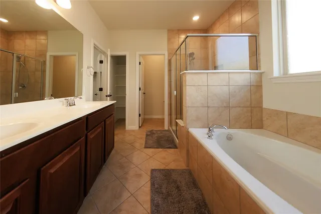 a spacious bathroom with a tub sink shower and mirror