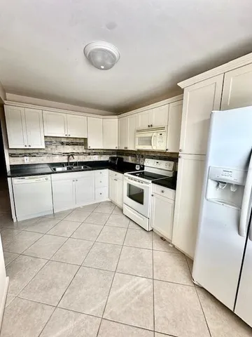 a kitchen with granite countertop white cabinets and white appliances