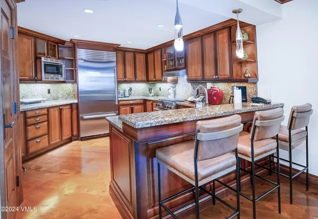 a kitchen with stainless steel appliances granite countertop a stove a sink dishwasher a microwave oven and a refrigerator with wooden cabinets