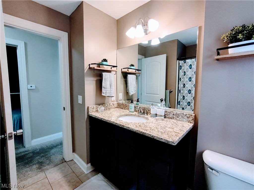 1468 Steese Road Uniontown, OH 44685 - Photo 15 of 28 Bathroom featuring tile flooring, vanity with extensive cabinet space, a notable chandelier, and toilet