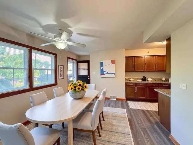 a kitchen with stainless steel appliances granite countertop a stove top oven a sink dishwasher a dining table and chairs with wooden floor