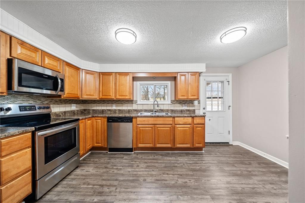 145 Lawrence Avenue Washington, PA 15301 - Photo 13 of 32 a large kitchen with granite countertop a stove top oven a sink dishwasher a dining table and chairs with wooden floor