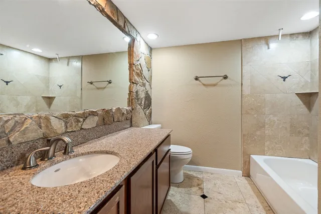 a bathroom with a granite countertop sink a toilet and shower